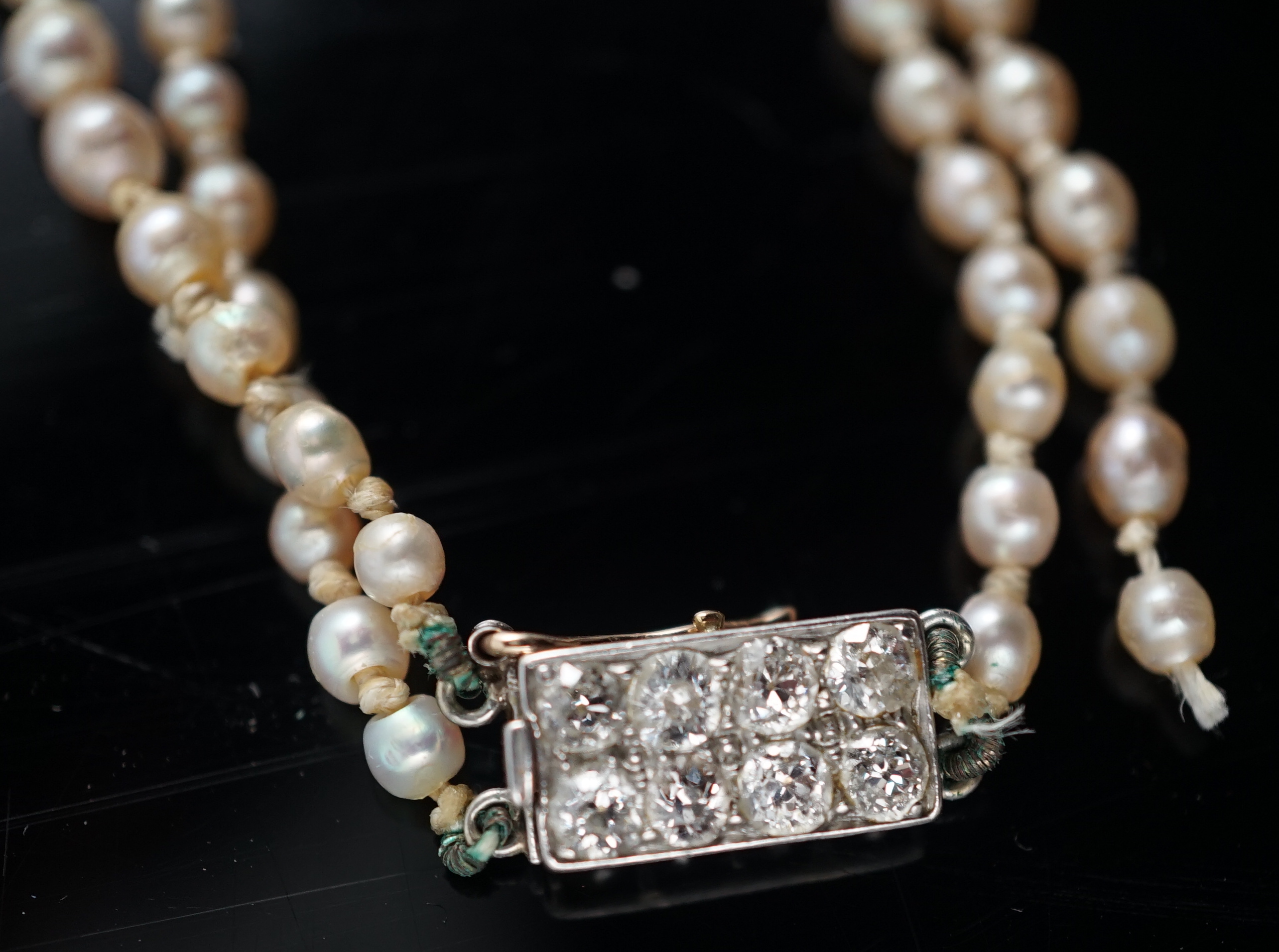 A twin strand graduated cultured pearl necklace, with gold and six stone diamond set rectangular clasp